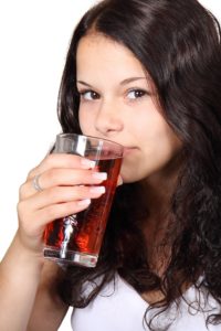 brunette woman drinking red cranberry juice out of a clear glass dietary myths