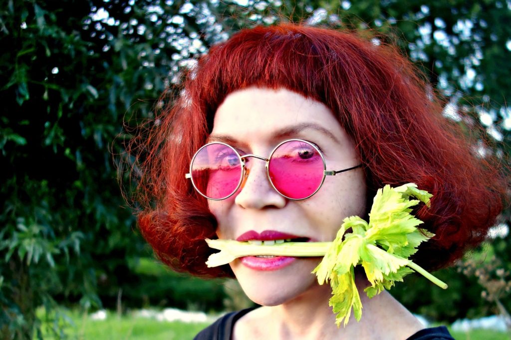 hipster woman eating celery red hair pink glasses